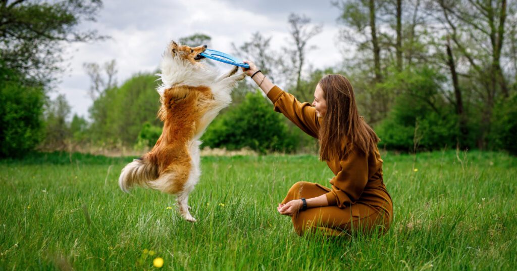 female owner playing outside with a dog