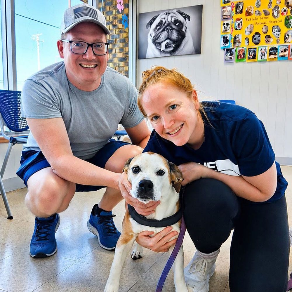 male and female posing with dog in waiting room