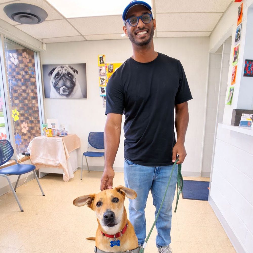 male owner posing for a picture with dog in waiting room