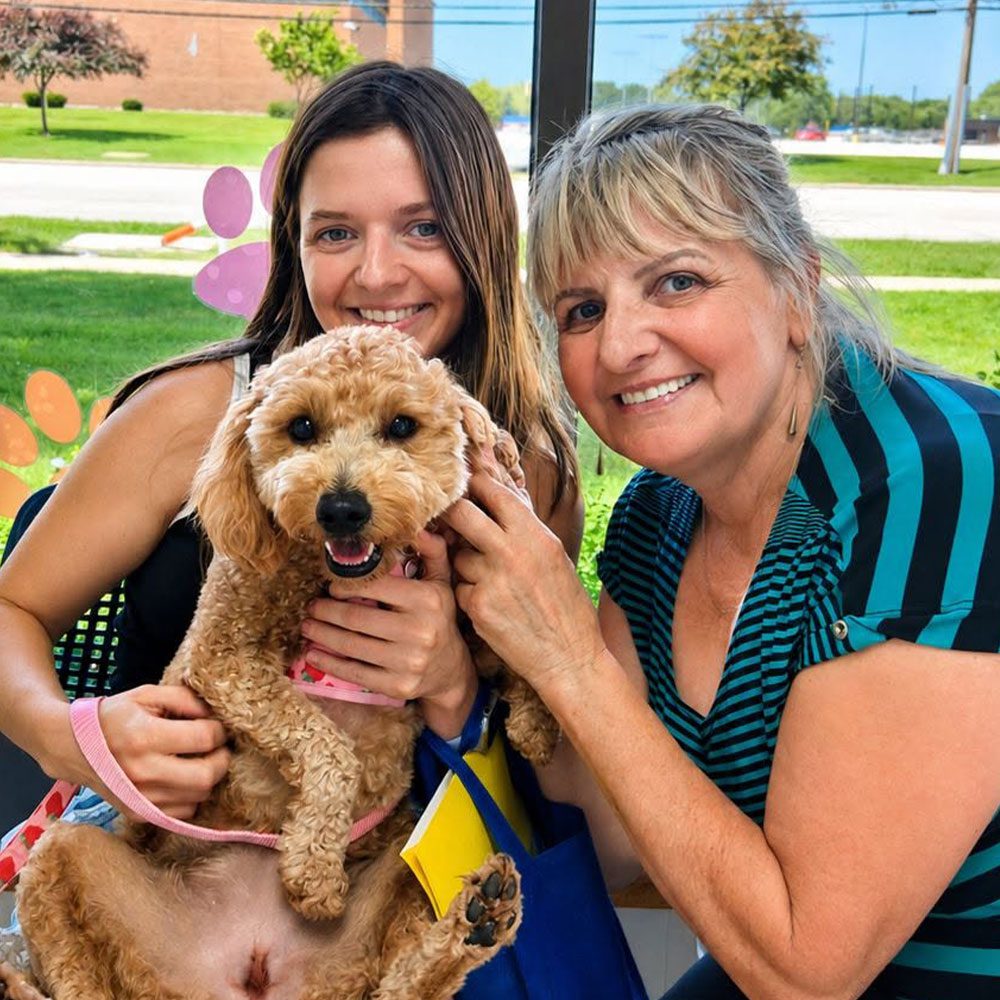 mom and daughter posing while holding dog in waiting room