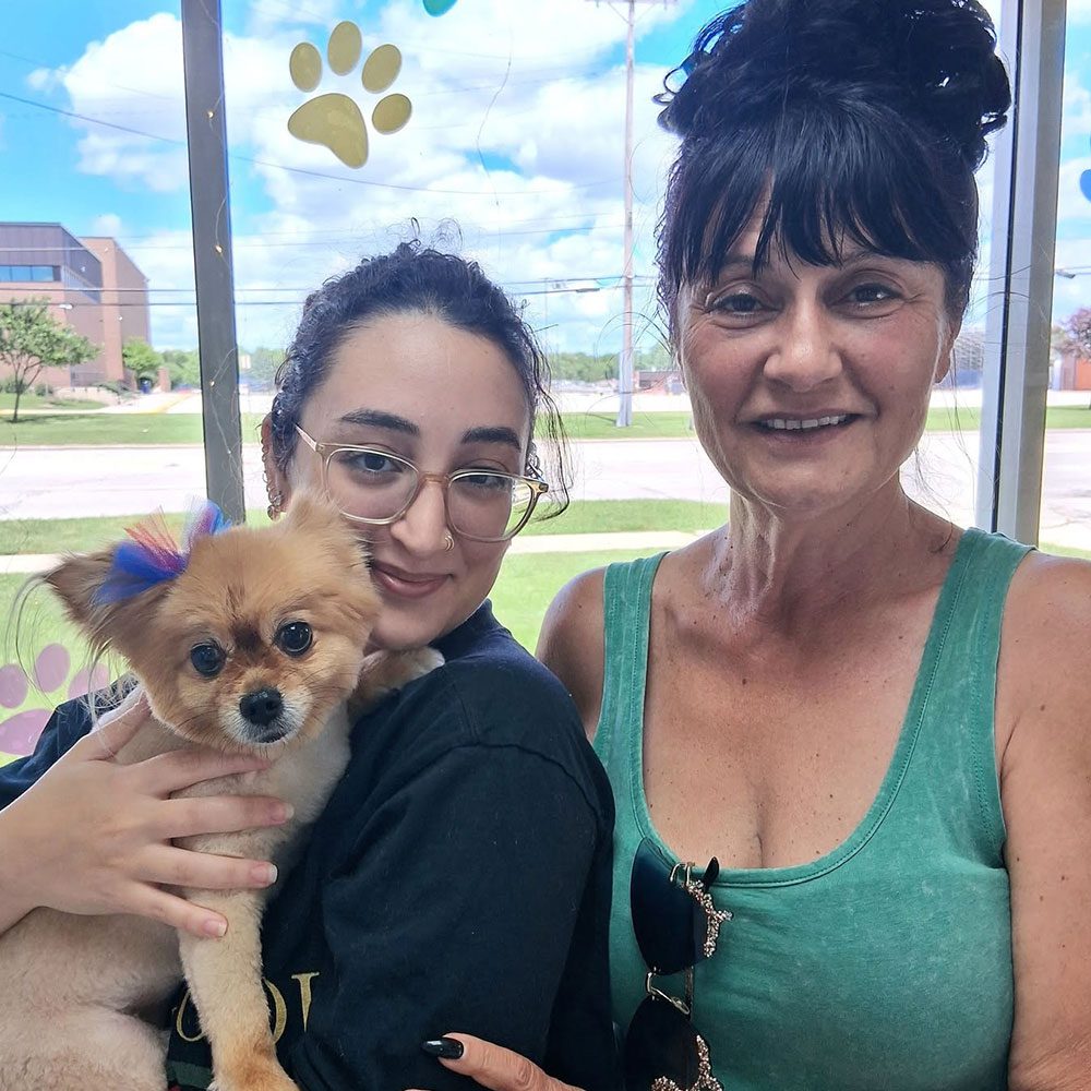 mom and daughter posing for picture with dog in waiting room
